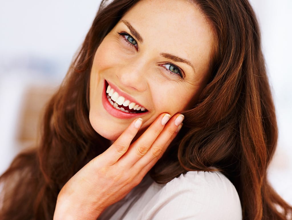 Woman smiling big while touching her face